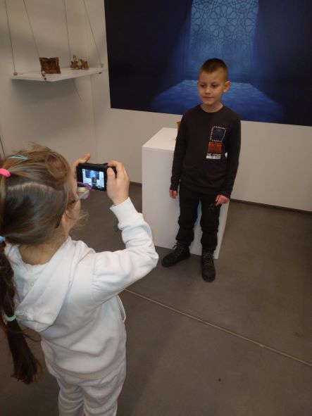 ucze fotografuje ucznia na tle wystawy